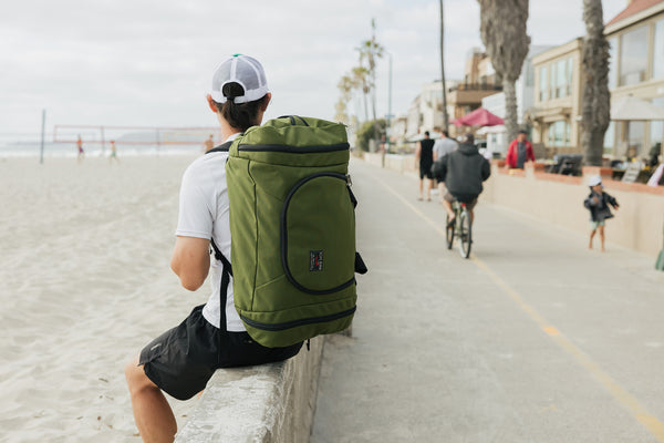 Person carrying an Aeronaut 45 sitting on the wall at the Venice Beach, CA boardwalk.